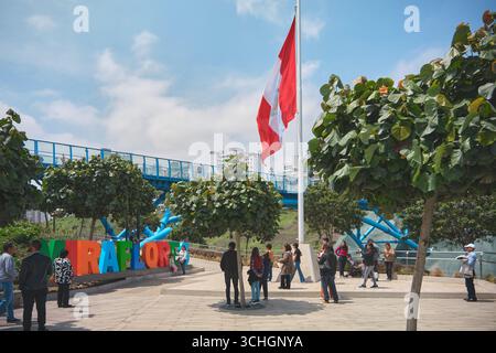 Lima perù agosto 30 2025: Turisti che visitano il parco di miraflores con il nuovo ponte la paz e la bandiera peruviana che sventola Foto Stock