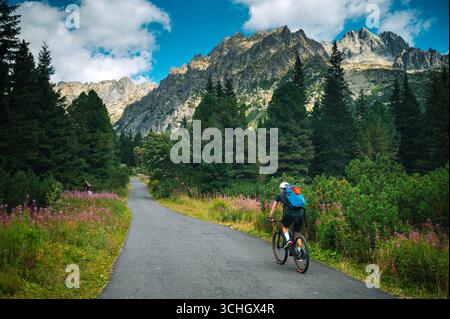 Un mountain bike corre lungo un sentiero nella foresta, navigando lungo il sentiero tortuoso attraverso il terreno alpino per un'impegnativa avventura all'aria aperta. Foto Stock