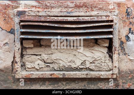 Primo piano di una vecchia presa d'aria con sfondo in mattoni, che mostra la consistenza, l'età e un senso di storia. Il metallo arrugginito e la vernice di pelatura si aggiungono a. Foto Stock