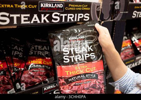 Una mano di chi acquista una bistecca Kirkland Signature Extra thick Steak Strips al Costco Foto Stock