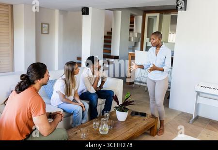 Gruppi diversi di amici diversi che hanno animato discussioni in un moderno salotto, a casa Foto Stock