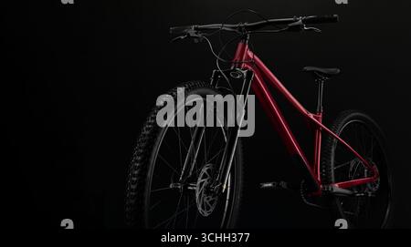 Moderna mountain bike hardtail rossa con forcella di sospensione e freni a disco isolati su sfondo nero Foto Stock