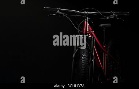 Vista frontale della moderna mountain bike hardtail rossa con forcella di sospensione e freni a disco su sfondo nero Foto Stock