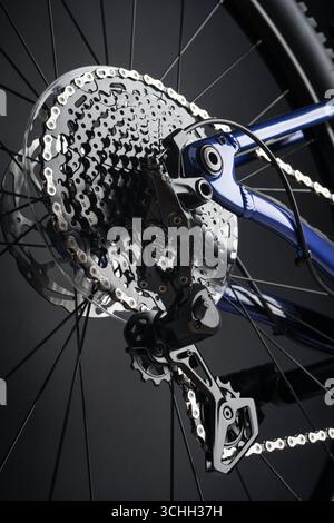 Una ripresa ad alta risoluzione e ad angolo basso di una nuova cassetta degli attrezzi e deragliatore posteriore di una bicicletta pulita su uno sfondo scuro e minimalista. Foto Stock