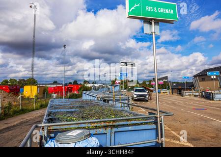 Rifiuti smistati collocati in contenitori di riciclaggio separati presso le stazioni municipali con auto parcheggiata. Svezia. Foto Stock