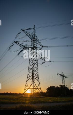 Pilone di trasmissione dell'elettricità ad alta tensione, noto anche come torre di trasmissione, fotografato dal basso al tramonto in Germania. Foto Stock