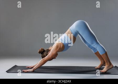 Le donne che praticano lo yoga si mettono in posa sul tappeto, concentrandosi sulla forza del nucleo, la flessibilità e il controllo del respiro. Foto Stock