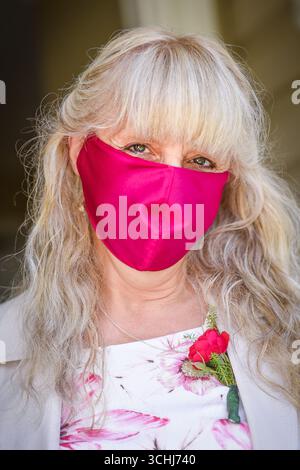 Donna che indossa una maschera rosa per sposarsi al Covid Times Foto Stock