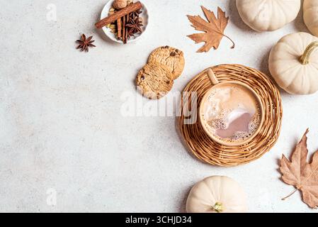 Concept design autunnale con bevanda piccante al caffè, zucche bianche, biscotti e foglie d'acero autunnale su sfondo bianco, vista dall'alto, spazio copia. Accogliente Foto Stock