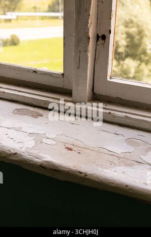 Una vista ravvicinata del davanzale di un vecchio edificio rivela segni di deterioramento della vernice Foto Stock