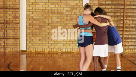 Ammassare quattro giocatori di basket che si appoggiano al basket nella palestra scolastica con abbigliamento sportivo, spazio fotocopie Foto Stock