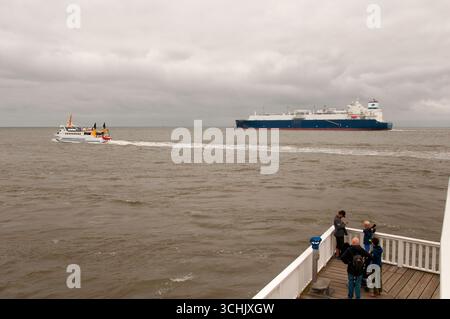 Immagine che mostra una grande nave portacontainer che passa di fronte alla città tedesca di Cuxhaven alla foce del fiume Elba Foto Stock