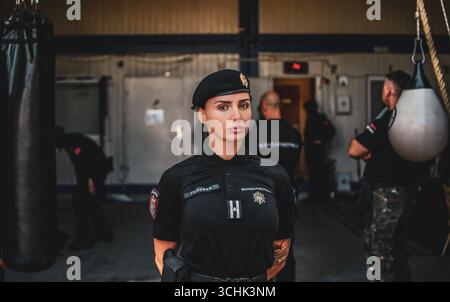 Ritratto di una donna della Gendarmeria in uniforme, in piedi all'interno di una base militare. Foto Stock