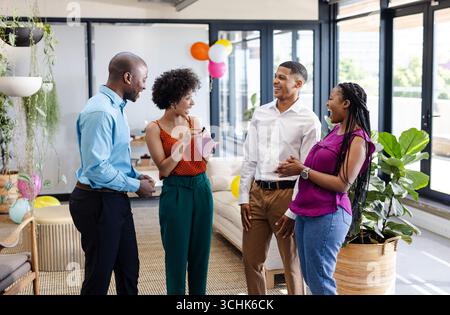 Diversi colleghi in ufficio ridono e discutono di idee durante una riunione informale Foto Stock