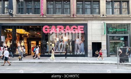 Montreal QC, Canada - 3 agosto 2025: Vetrina del Garage con segnaletica e sfilate di moda, circondato da diversi pedoni in un vivace urba Foto Stock