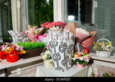 Una collezione di vivaci bouquet floreali esposti in confezioni creative su davanzale. la scena include una varietà di fiori e un cestino decorativo Foto Stock
