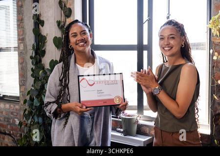 Donne sorridenti che celebrano i risultati aziendali con un certificato in un ufficio moderno Foto Stock