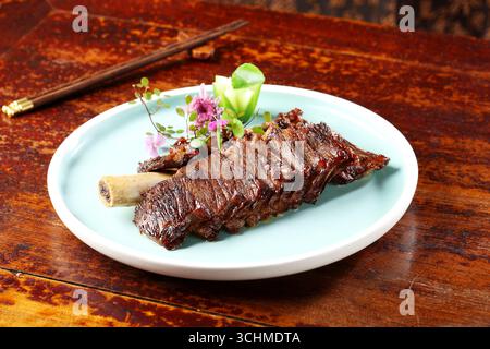 Costolette di manzo ossa tagliate su piatto di acqua con fiori commestibili Foto Stock