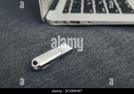 L'unità USB Silver è posizionata su un computer portatile. Il computer portatile è aperto e l'unità USB non è collegata Foto Stock