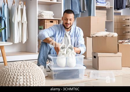 Giovane uomo che mette le scarpe in un contenitore nel guardaroba Foto Stock