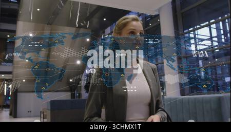 Analizzando la mappa olografica, i dirigenti indossano un blazer grigio nella hall aziendale con colonne metalliche Foto Stock