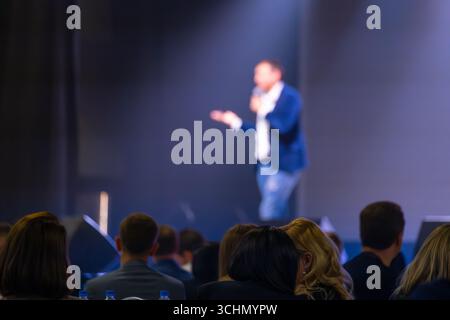 Relatore che offre una presentazione a un pubblico impegnato in una conferenza aziendale con un'atmosfera mirata. Foto Stock