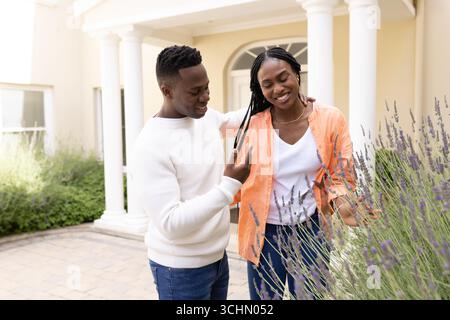 Coppia afroamericana che si diverte insieme in giardino, sorridente e rilassata Foto Stock