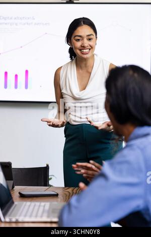 Presentazione dei dati a una collega, donna d'affari sorridente che conduce una riunione in ufficio Foto Stock