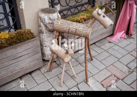 Due stravaganti sculture di cervi fatte di tronchi d'albero si trovano in un ambiente urbano sul marciapiede Foto Stock