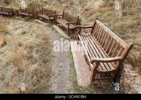 Fila di vecchie panchine commemorative in legno a Sidmouth, nel Devon orientale Foto Stock