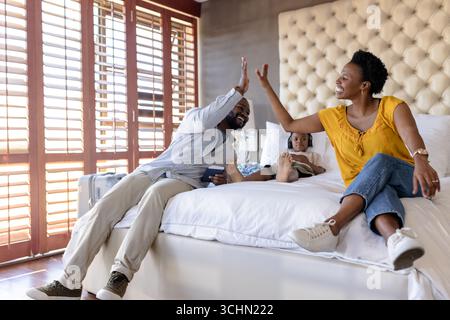 Famiglia che si diverte a trascorrere momenti di qualità, i genitori danno cinque a letto con il bambino Foto Stock
