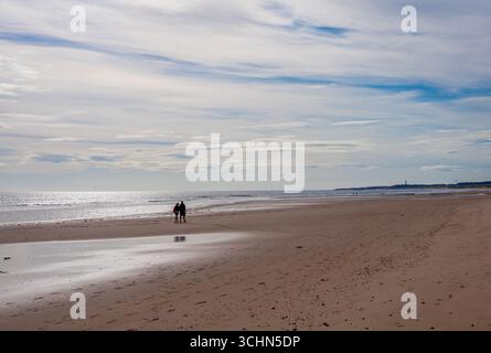 Coppia che cammina lungo la spiaggia di Drudge Bay con la bassa marea Foto Stock