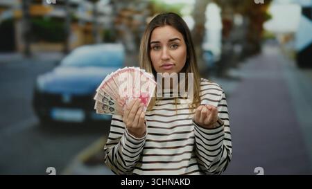 Donna che tiene all'aperto la corona islandese con un'espressione premurosa sullo sfondo di una strada cittadina. Foto Stock