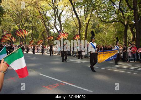 La East Meadow High School marching band si esibisce con bandiere colorate durante la Columbus Day Parade sulla 5th Avenue, New York City, come folla tifo Foto Stock