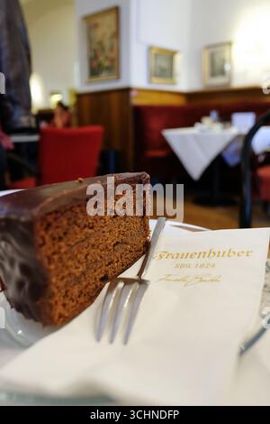 Fetta di Sachertorte viennese, una tradizionale torta austriaca a strati di marmellata di albicocche e ricoperta di glassa di cioccolato fondente, servita nel famoso caffè Foto Stock