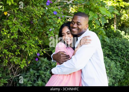 Abbracciando con gioia, coppia che celebra il matrimonio nel lussureggiante giardino con felicità Foto Stock