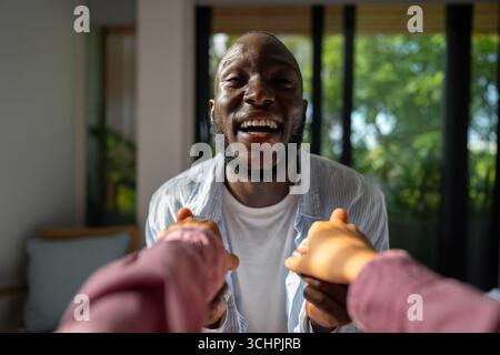 Giovani coppie diverse che sorridono gioiosamente insieme nel loro luminoso soggiorno, indossando abiti casual Foto Stock