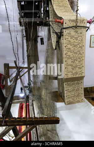 sari di seta che sventolano uno strumento di artigianato vecchiotto sul telaio a mano in un ambiente interno Foto Stock
