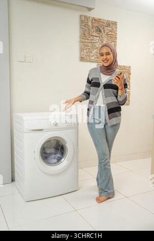 Una donna che mostra un'innovativa lavatrice moderna in un elegante spazio interno Foto Stock