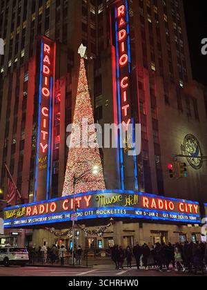 Luci e decorazioni natalizie all'esterno della famosa sede di concerti radio City Music Hall nel Rockefeller Center, Manhattan, New York, di notte. Foto Stock