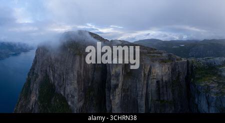 Dalla nebbia emergono scogliere torreggianti, in piedi di guardia sui tranquilli fiordi di Norways. Questo paesaggio mozzafiato cattura l'essenza della tortuosa strada curva di Lysefjorden, il fiordo norvegese fino a Lysebotn Foto Stock