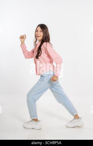 Una giovane donna gioiosa che indossa un outfit casual mentre danza energicamente e liberamente Foto Stock