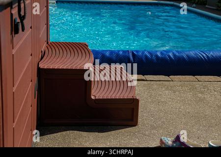 Scala in plastica marrone per vasca idromassaggio accanto alla piscina coperta Foto Stock