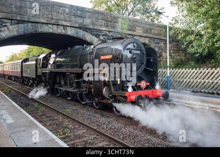 Britannia, una locomotiva britannica a vapore conservata 70000, arriva a Long Preston nel North Yorkshire e sta prendendo l'acqua prima di procedere. Foto Stock