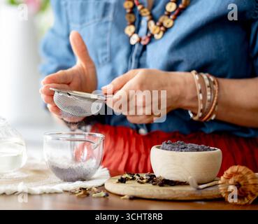 Donna che prepara il tè Blue Matcha e lo setaccia attraverso Un Strainer Foto Stock