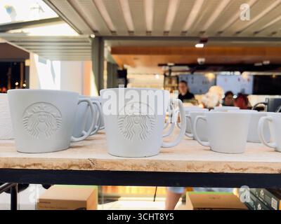 Alicante, Spagna - 30 agosto 2025: Caffetteria Starbucks presenta tazze in ceramica bianca con logo in esposizione, creando un'atmosfera calda e invitante Foto Stock