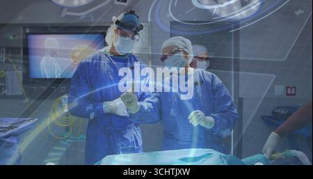 Due chirurghi in scrubbing che gestiscono l'interfaccia olografica sopra il tavolo in sala operatoria Foto Stock