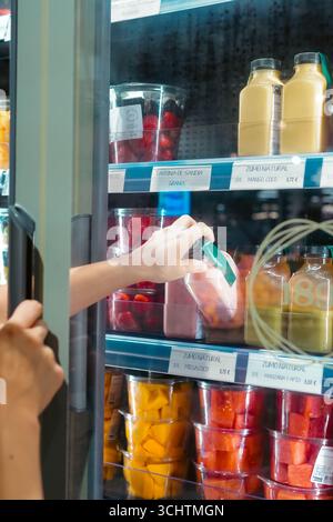 Barcellona, Spagna - 30 agosto 2025 ; Una giovane donna in cerca di succo fresco dal frigorifero del supermercato Foto Stock