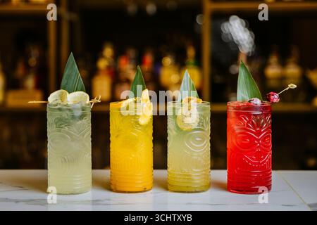 Colorati cocktail tiki con decorazioni tropicali sul bancone del bar, vivaci e rinfrescanti Foto Stock