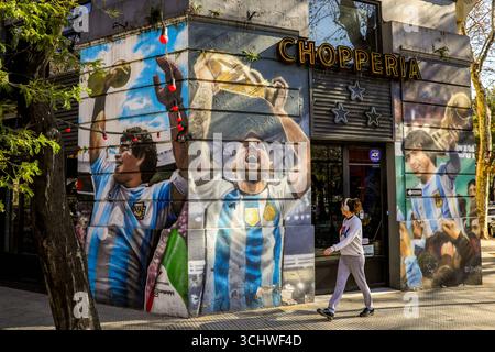 Turismo in Argentina Una donna cammina davanti a un pub adornato con grandi dipinti di argentine tre capitani della Coppa del mondo di calcio FIFA che tengono la Coppa del mondo, a Buenos Aires, Argentina, 21 luglio 2025. Gli amati capitani di calcio argentini raffigurati sulle pareti sono L-R Diego Armando Maradona, Lionel messi e Daniel Alberto Passarella. BUENOS AIRES Argentina Copyright: XMatrixxImagesx/xDiegoxAzubelx Foto Stock